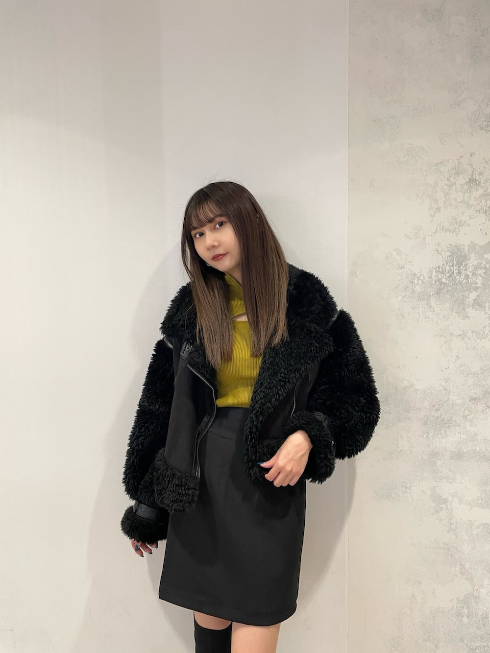 ブラック系のムートンコート、イエロー系のニット/セーター、ブラック系のスカートを着用したレディースの秋コーディネートの4枚目の写真