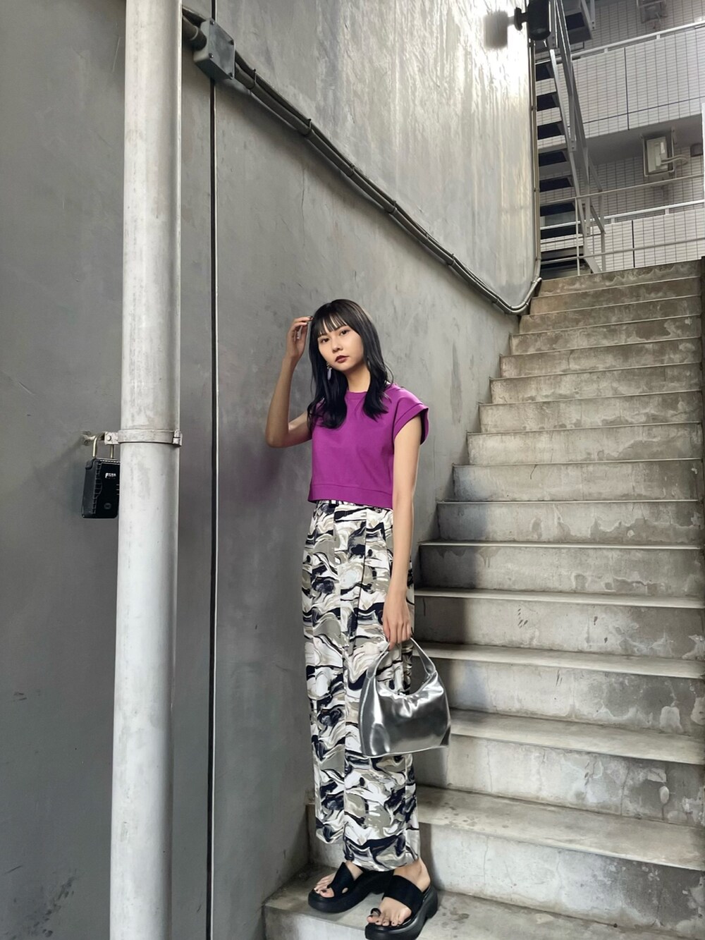 パープル系のタンクトップ、シルバー系のハンドバッグ、ブルー系のスラックスを着用したレディースの春コーディネートの2枚目の写真