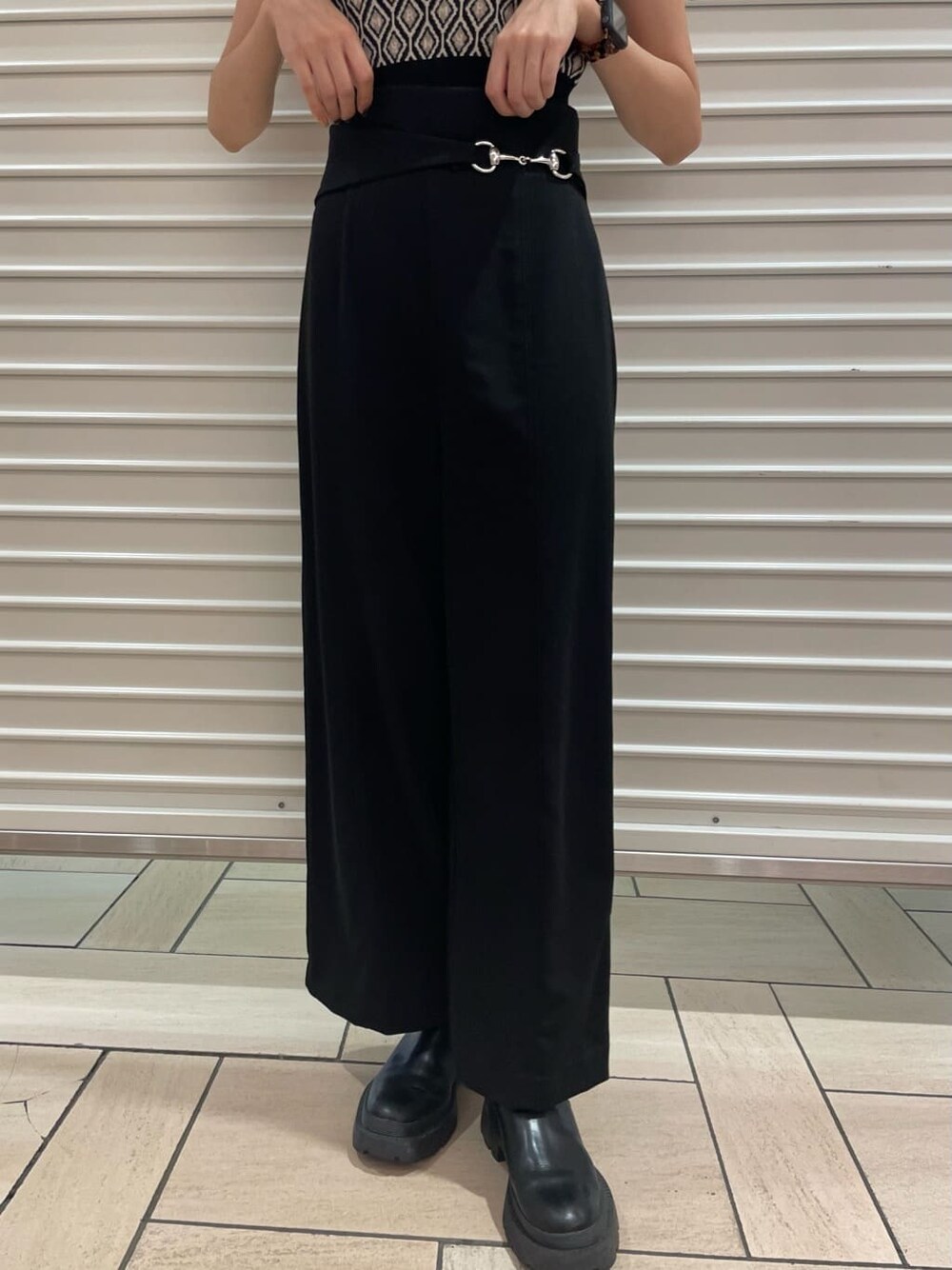 ブラック系のスラックス、ブラック系のニット/セーター、グリーン系のステンカラーコートを着用したレディースの夏コーディネートの7枚目の写真