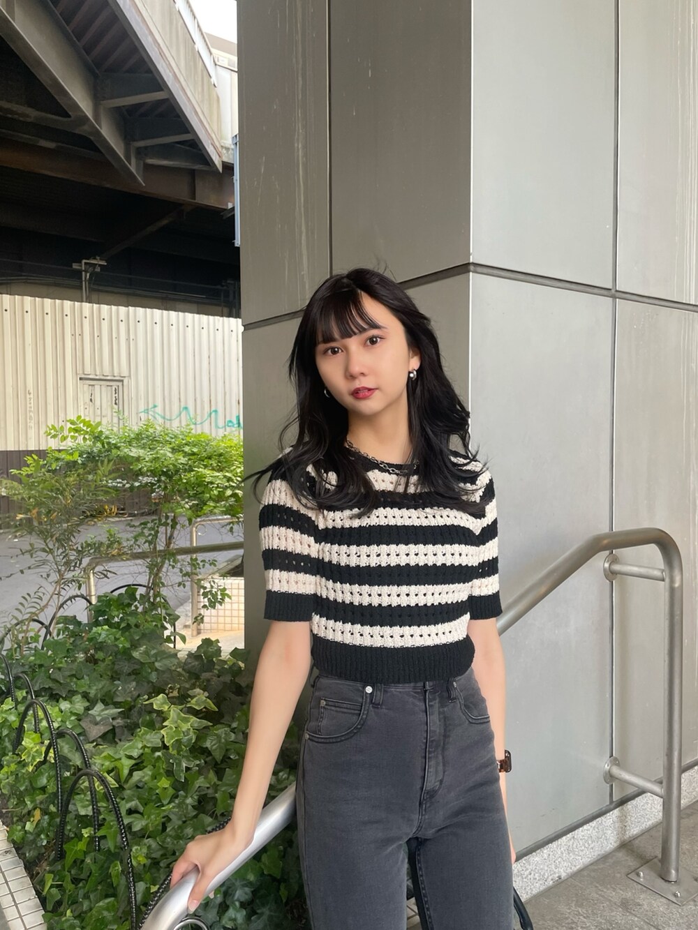 ブラック系のニット/セーター、グレー系のデニムパンツ、ブラック系のサンダルを着用したレディースの春コーディネートの3枚目の写真