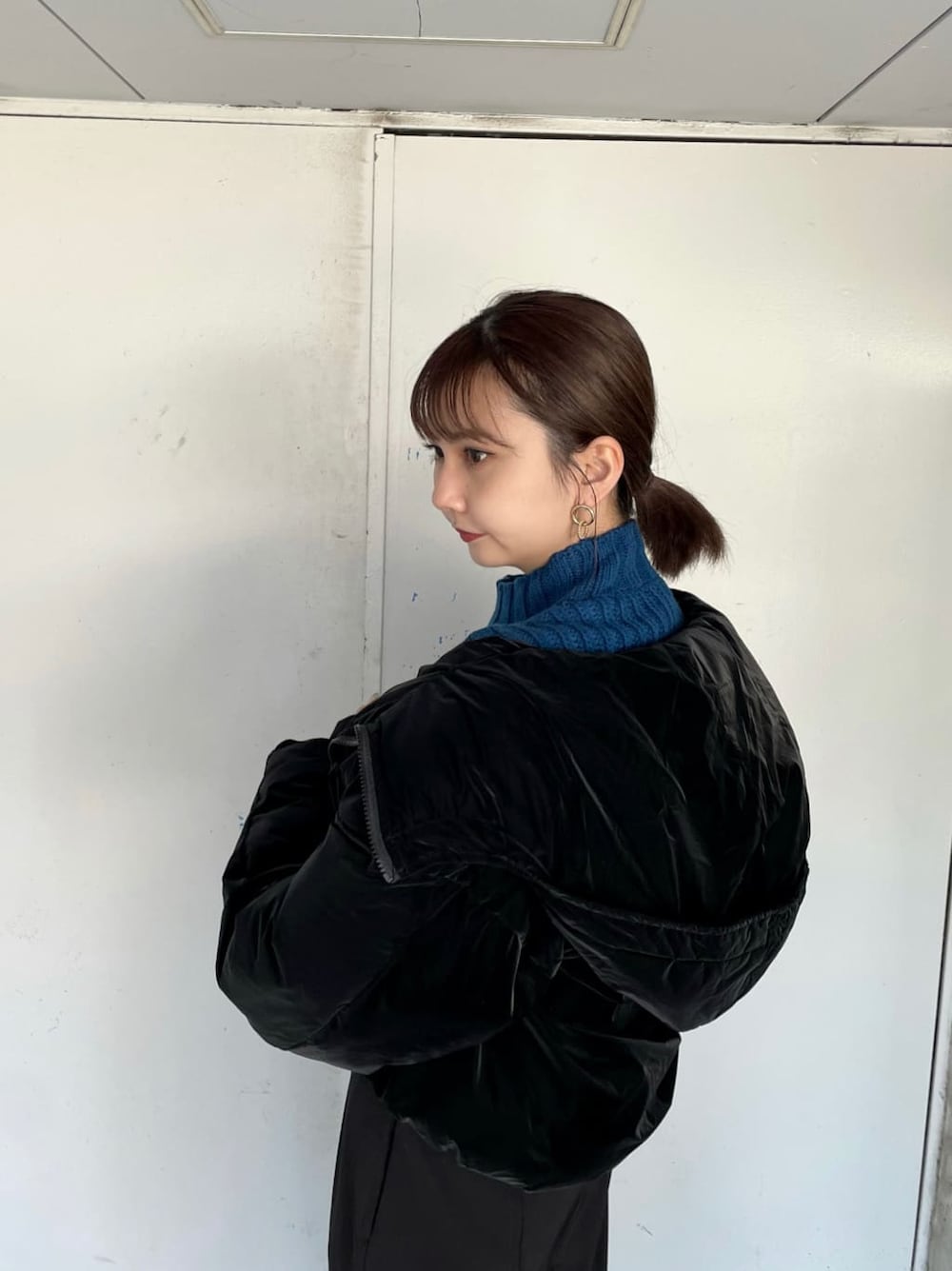 ブラック系のダウンジャケット/コート、ブラック系のスラックス、ブルー系のニット/セーターを着用したレディースの秋コーディネートの3枚目の写真