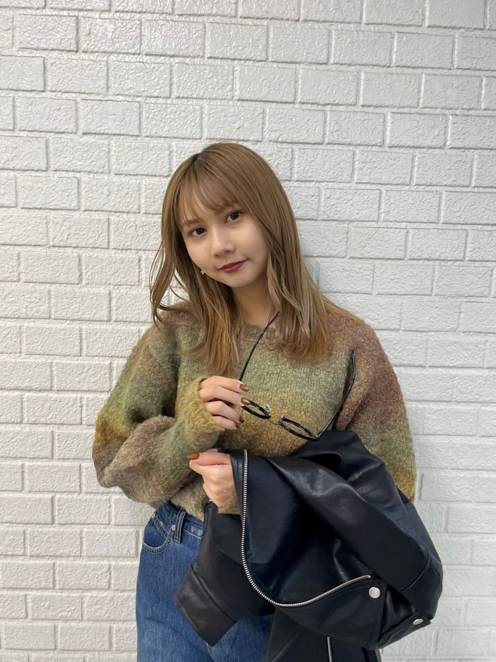 ブラック系のライダースジャケット、ホワイト系のブーツ、ブルー系のデニムパンツを着用したレディースの秋コーディネートの5枚目の写真