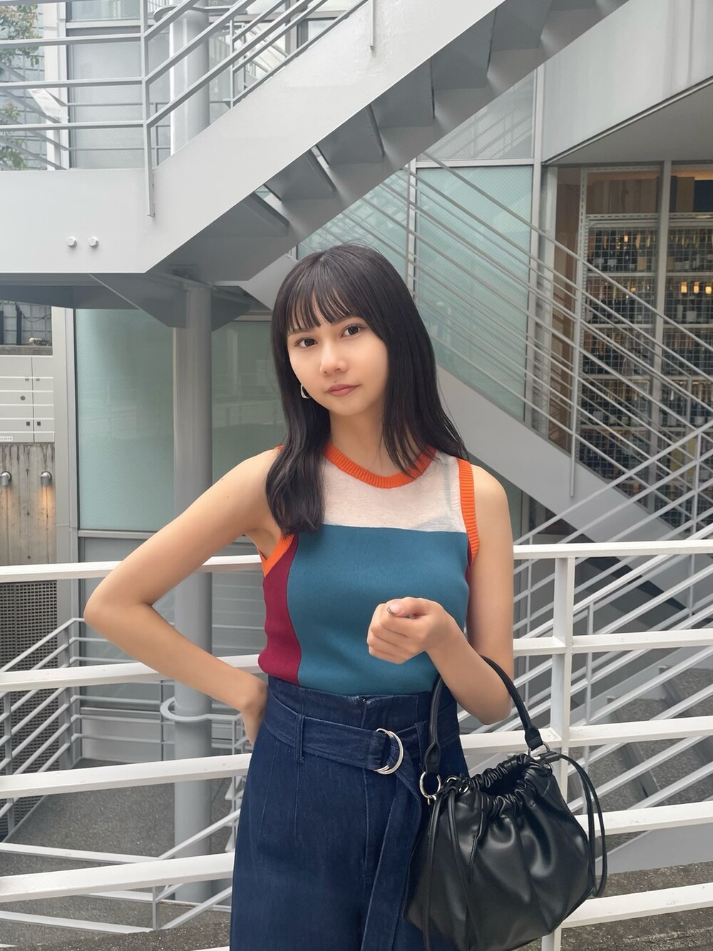ブルー系のニット/セーター、ブラック系のハンドバッグ、ブルー系のデニムパンツを着用したレディースの春コーディネートの4枚目の写真