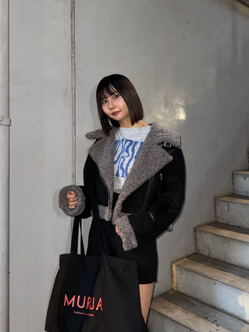 ブラック系のハンドバッグ、グレー系のニット/セーター、ブラック系のムートンコートを着用したレディースの冬コーディネートの2枚目の写真