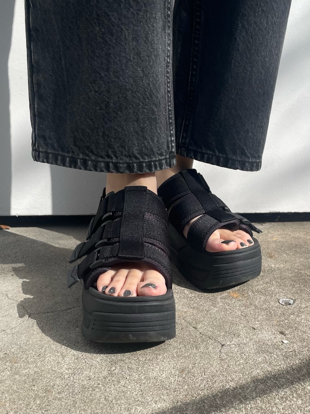 ブラック系のデニムパンツ、ブラック系のサンダル、ブラック系のポロシャツを着用したレディースの冬コーディネートの7枚目の写真