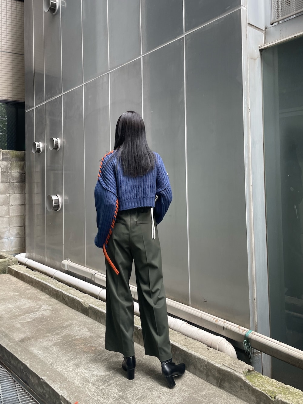 ブルー系のニット/セーター、グリーン系のスラックス、ブラック系のブーツを着用したレディースの夏コーディネートの3枚目の写真