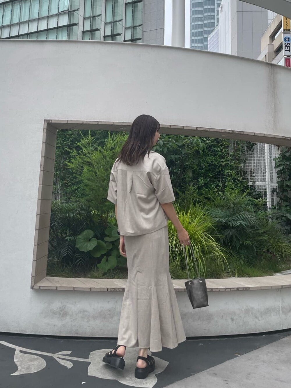 グリーン系のタンクトップ、ブラック系のサンダル、ブラック系のショルダーバッグを着用したレディースの夏コーディネートの3枚目の写真