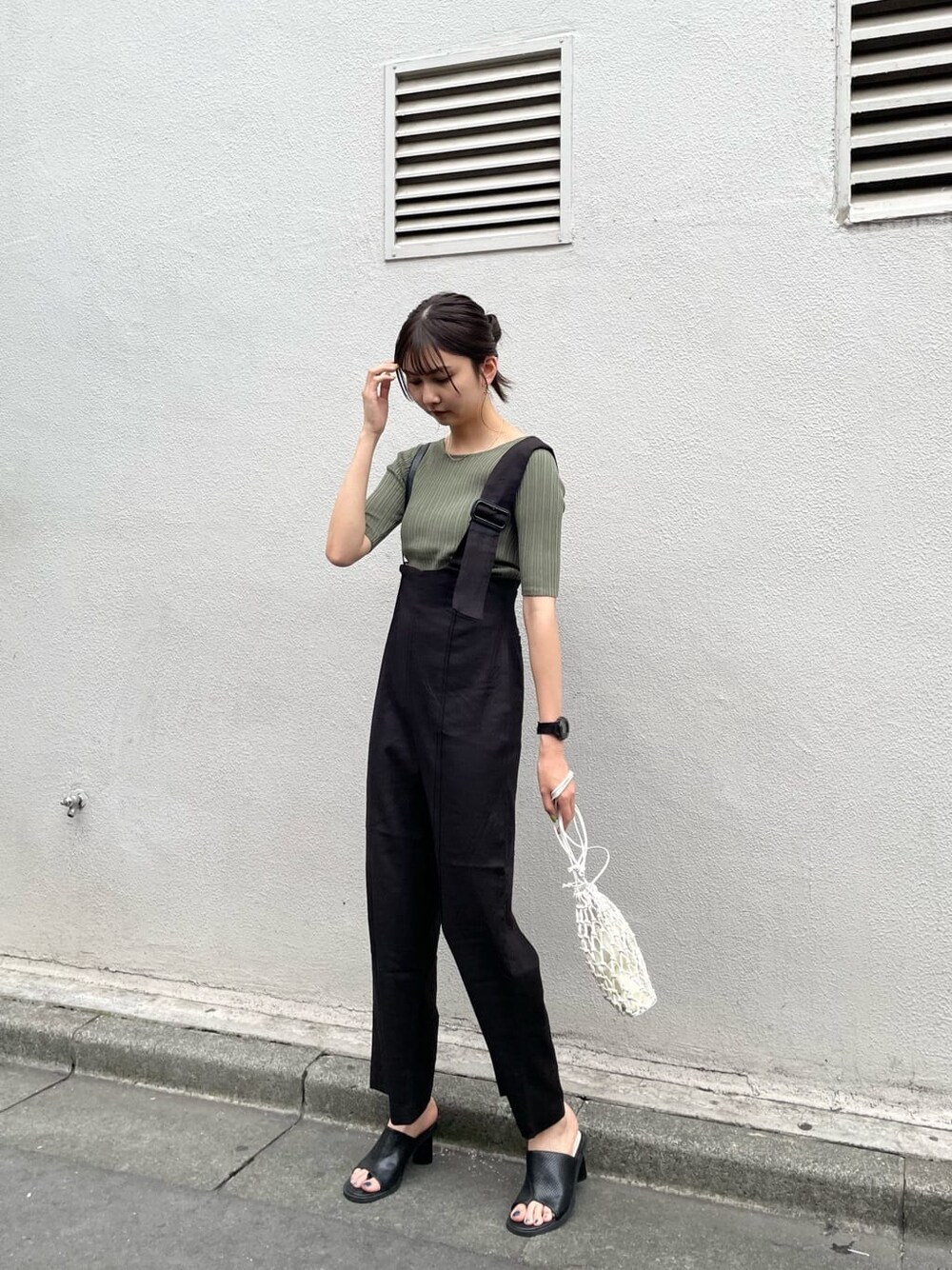 ブラック系のつなぎ/オールインワン、ホワイト系のハンドバッグ、グリーン系のニット/セーターを着用したレディースの春コーディネートの2枚目の写真