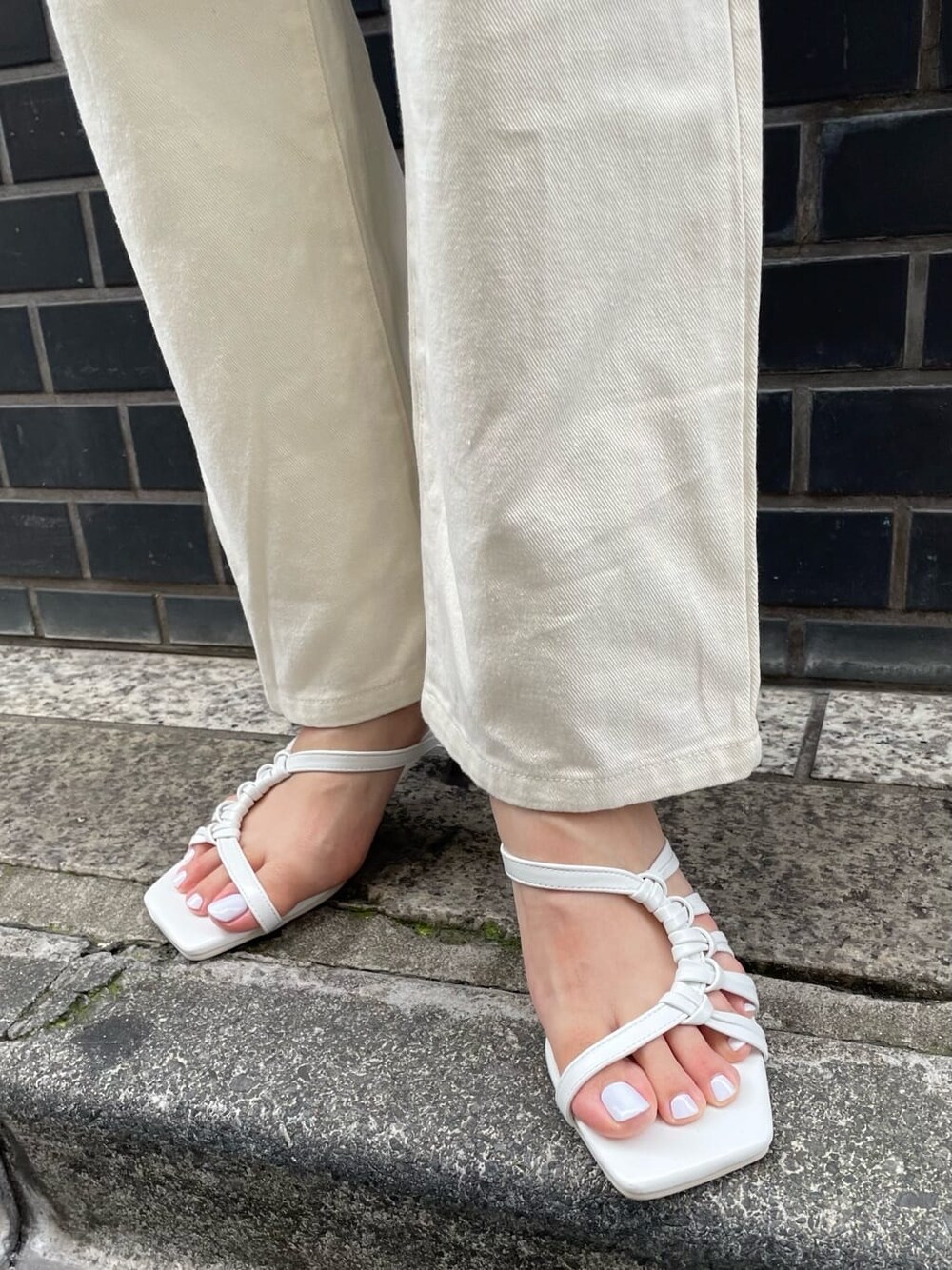 ホワイト系のデニムパンツ、ホワイト系のサンダル、グレー系のニット/セーターを着用したレディースの夏コーディネートの7枚目の写真