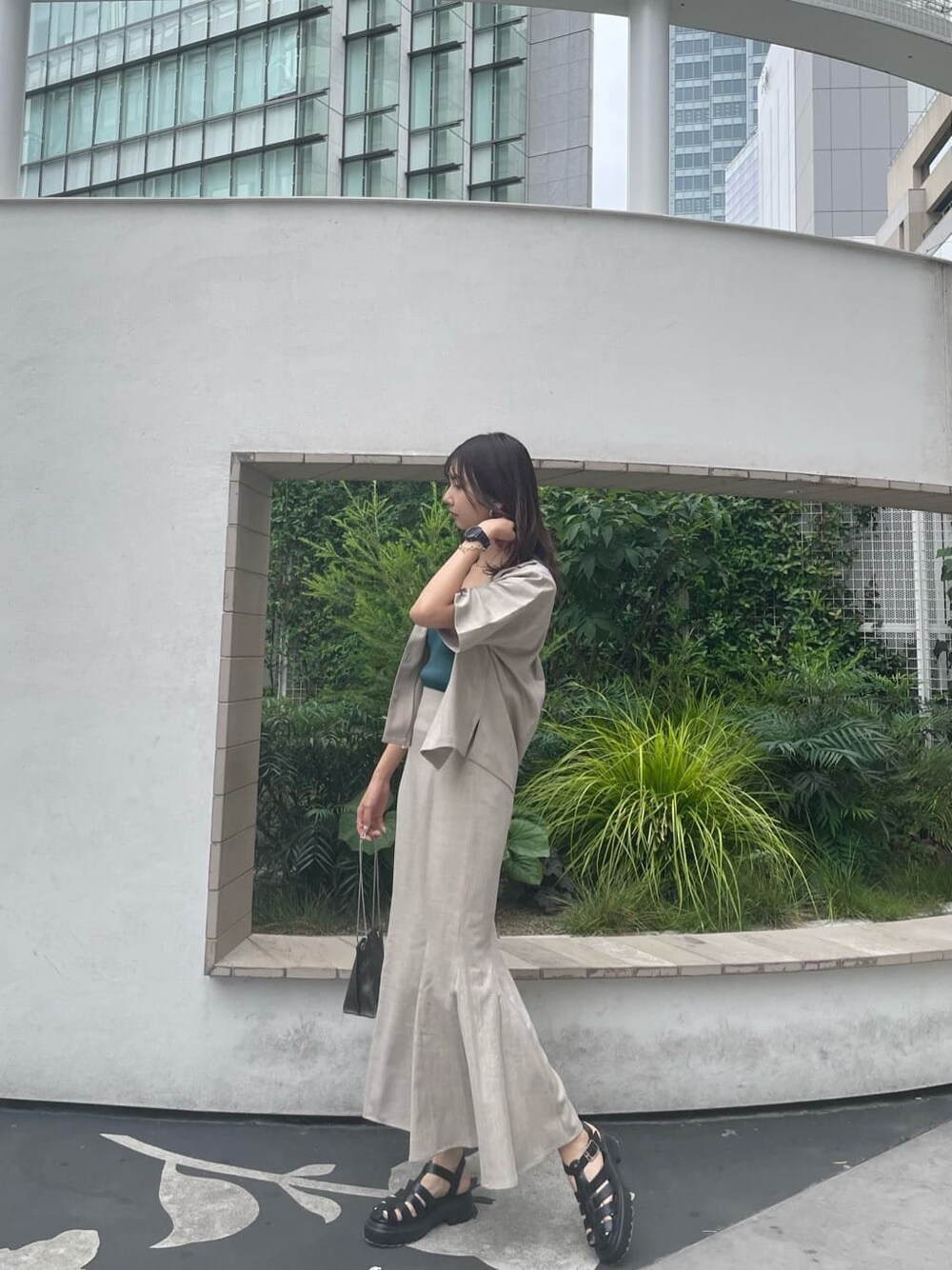 グリーン系のタンクトップ、ブラック系のサンダル、ブラック系のショルダーバッグを着用したレディースの夏コーディネートの2枚目の写真