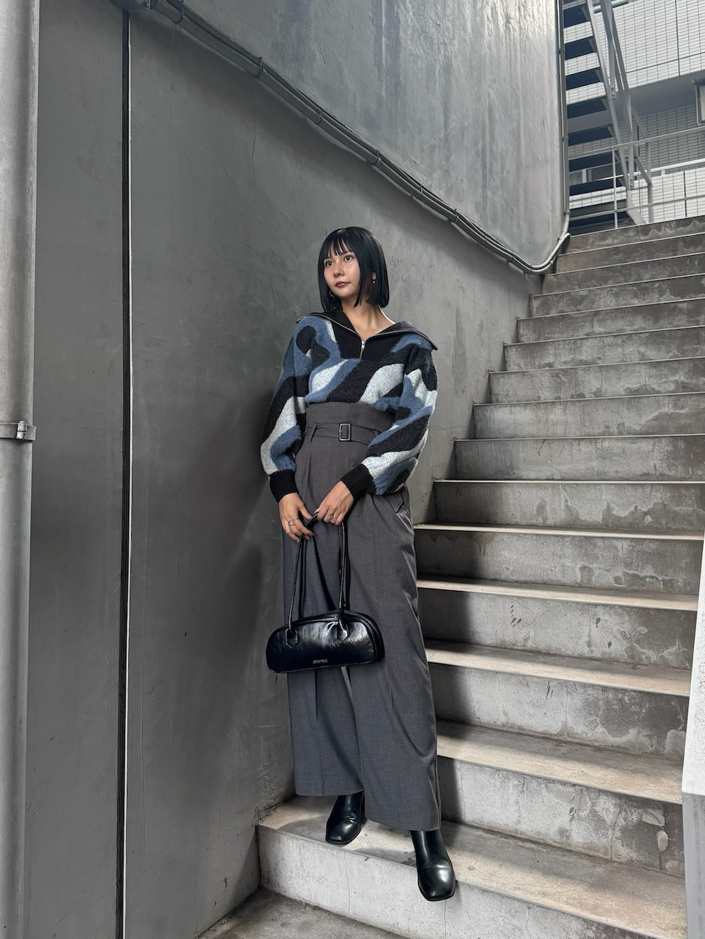 ブルー系のニット/セーター、グレー系のその他パンツ、ブラック系のブーツを着用したレディースの秋コーディネートの2枚目の写真