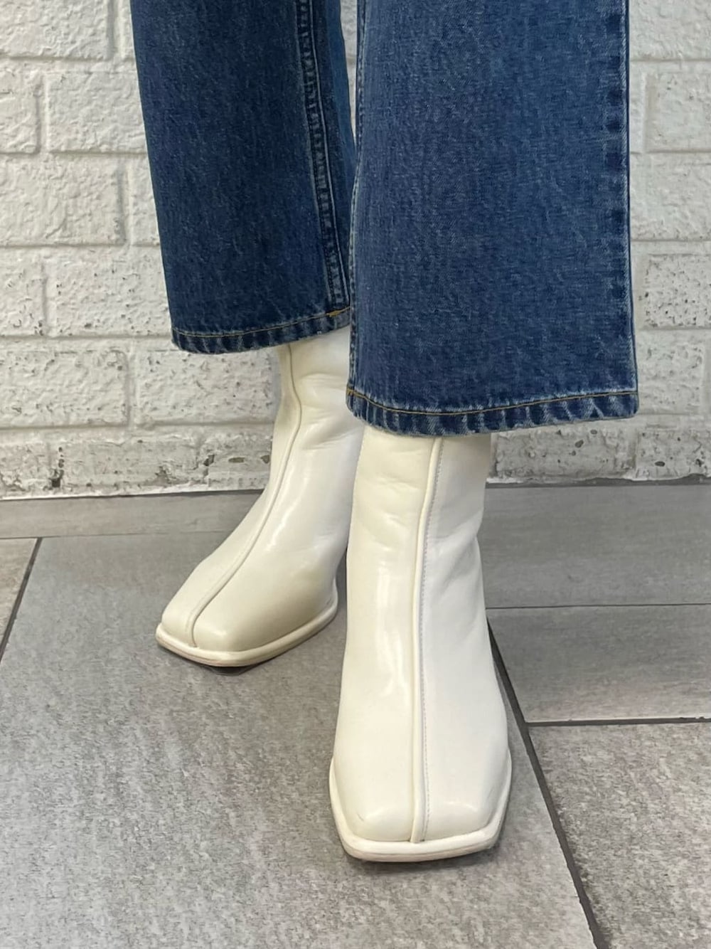 ブラック系のライダースジャケット、ホワイト系のブーツ、ブルー系のデニムパンツを着用したレディースの秋コーディネートの7枚目の写真