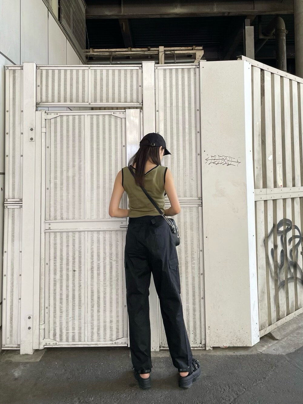 ベージュ系のタンクトップ、ブラック系のカーゴパンツ、ブラック系のサンダルを着用したレディースの夏コーディネートの3枚目の写真