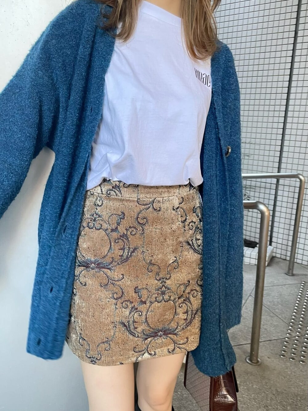 ホワイト系のTシャツ/カットソー、ブラウン系のスカート、ブルー系のカーディガン/ボレロを着用したレディースの秋コーディネートの5枚目の写真