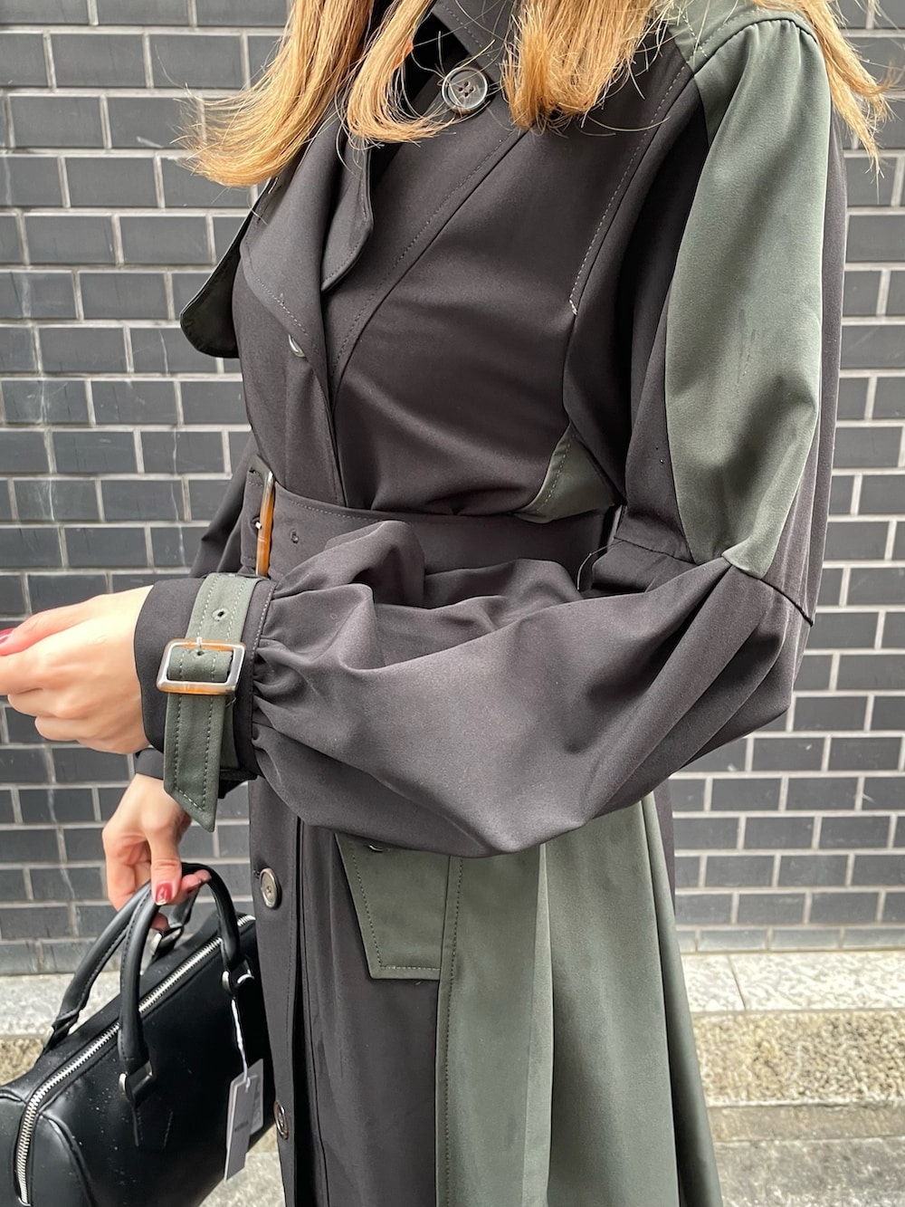 オレンジ系のニット/セーター、ブラック系のハンドバッグ、ブラック系のトレンチコートを着用したレディースの冬コーディネートの5枚目の写真