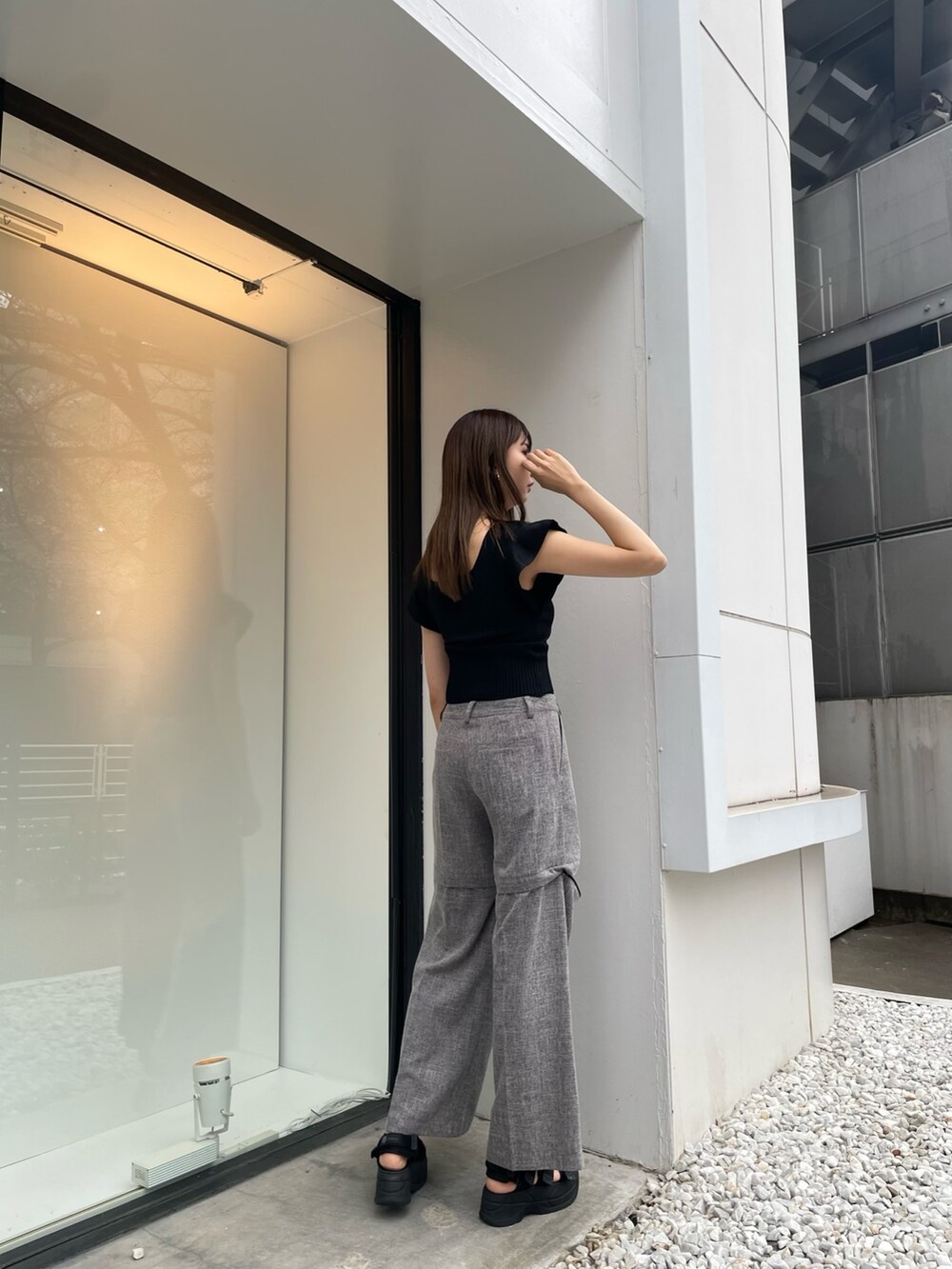 ブラック系のニット/セーター、グレー系のスラックス、ブラック系のサンダルを着用したレディースの春コーディネートの3枚目の写真