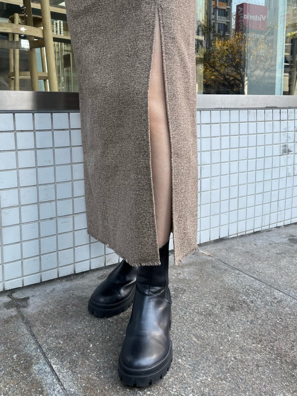 グレー系のニット/セーター、ブラウン系のスカート、ブラック系のブーツを着用したレディースの秋コーディネートの6枚目の写真