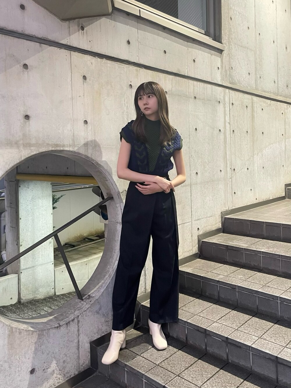 グリーン系のニット/セーター、ブラック系のスラックス、ホワイト系のブーツを着用したレディースの夏コーディネートの2枚目の写真