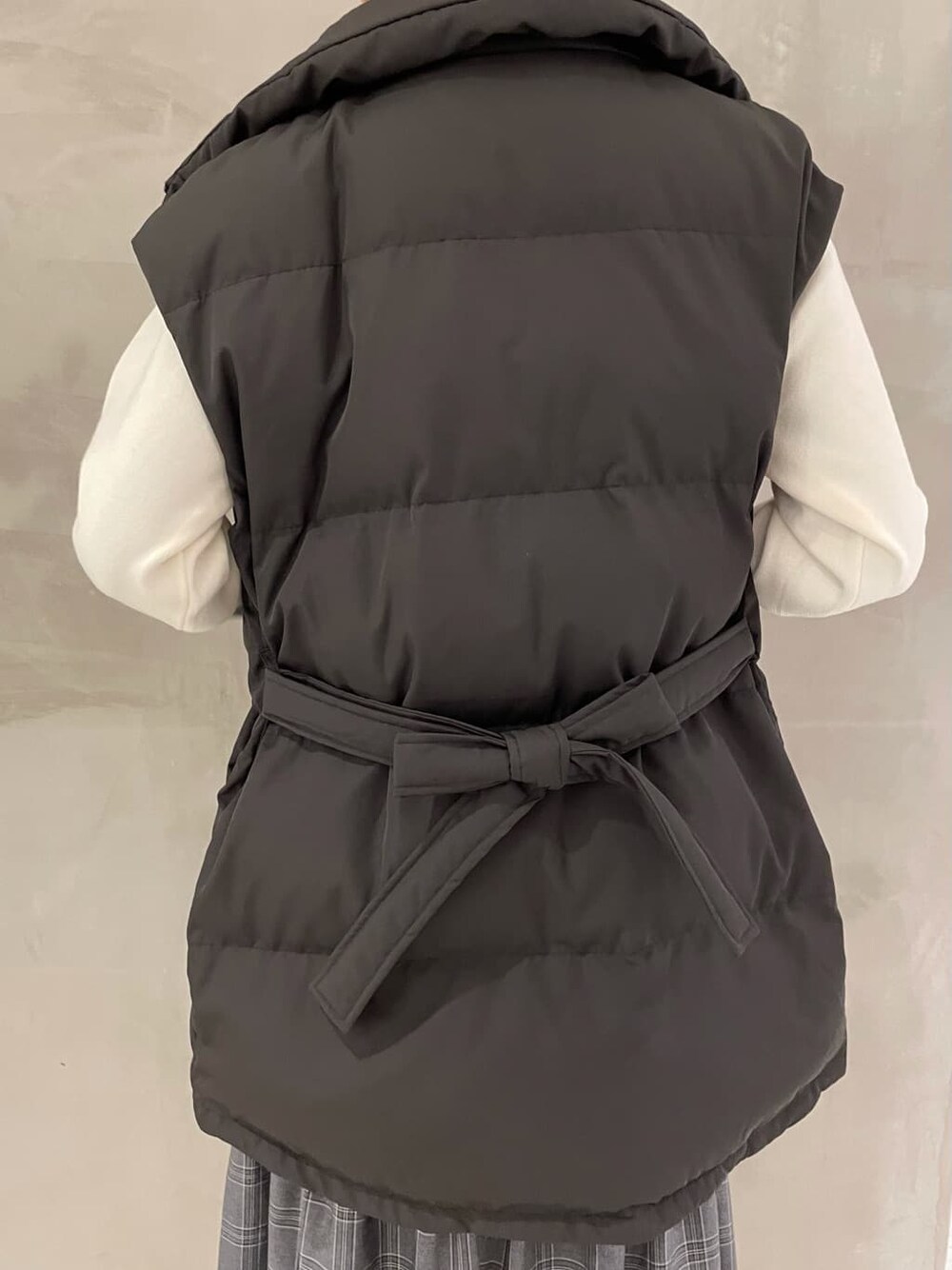 ブラック系のダウンベスト、その他のスカート、ブラウン系のブーツを着用したレディースの秋コーディネートの6枚目の写真