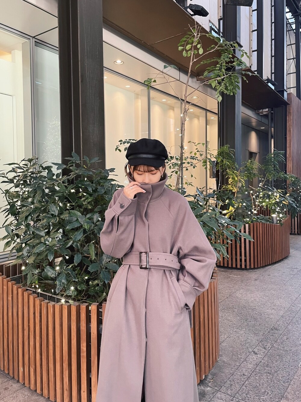 ブラウン系のステンカラーコートを着用したレディースの冬コーディネートの4枚目の写真