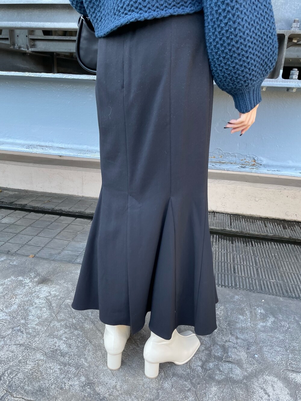 ブルー系のニット/セーター、ブラック系のハンドバッグ、ブラック系のスカートを着用したレディースの冬コーディネートの8枚目の写真