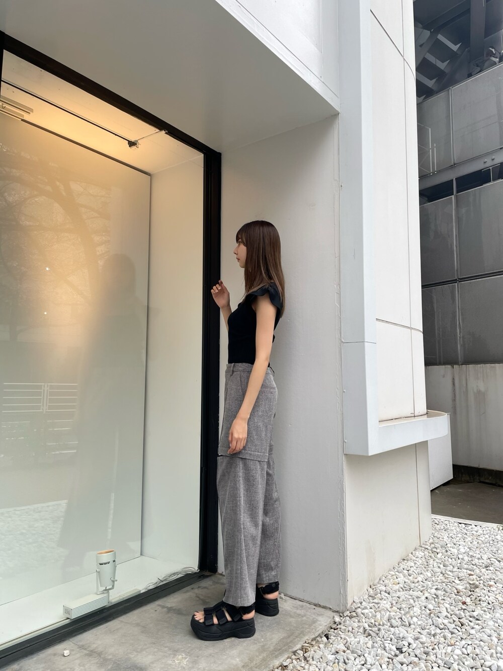 ブラック系のニット/セーター、グレー系のスラックス、ブラック系のサンダルを着用したレディースの春コーディネートの2枚目の写真