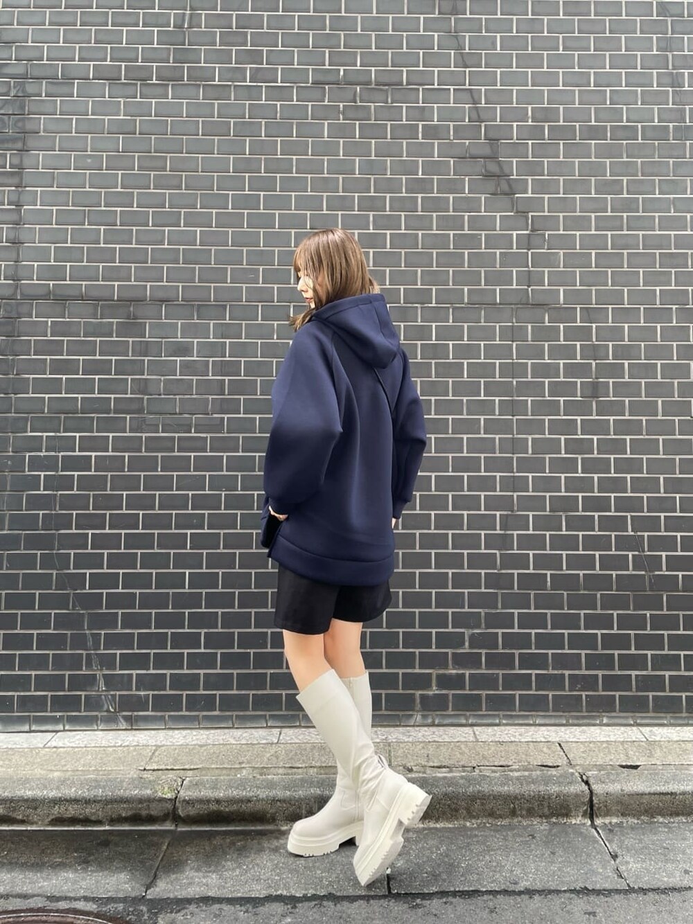 ホワイト系のブーツ、ベージュ系のショルダーバッグ、ブルー系のパーカーを着用したレディースの秋コーディネートの2枚目の写真