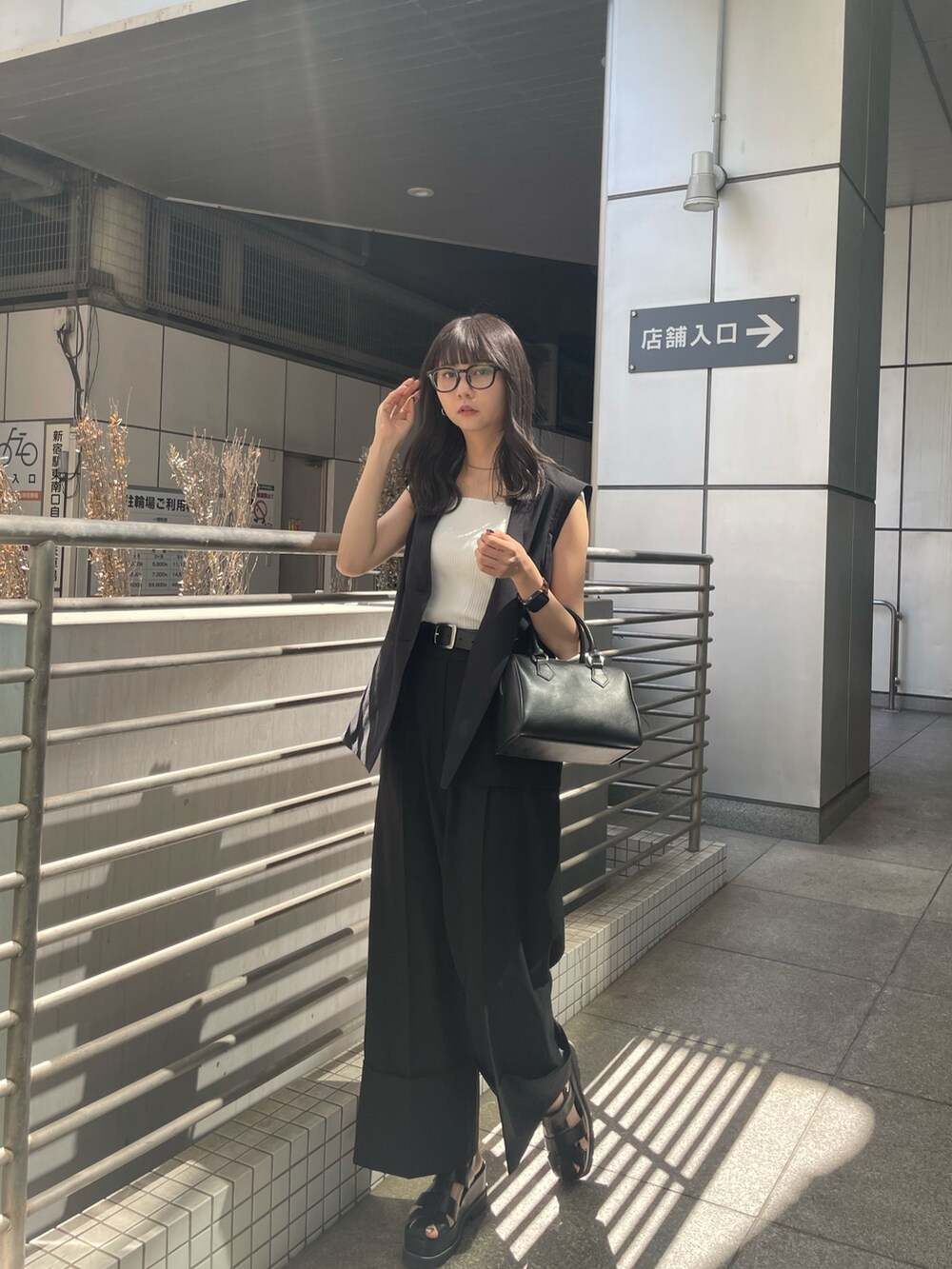 ブラック系のテーラードジャケット、ホワイト系のタンクトップ、ブラック系のスラックスを着用したレディースの春コーディネートの2枚目の写真