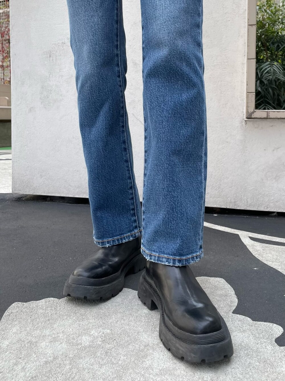 ブラック系のブーツ、ブルー系のデニムパンツ、ブラック系のハンドバッグを着用したレディースの春コーディネートの7枚目の写真