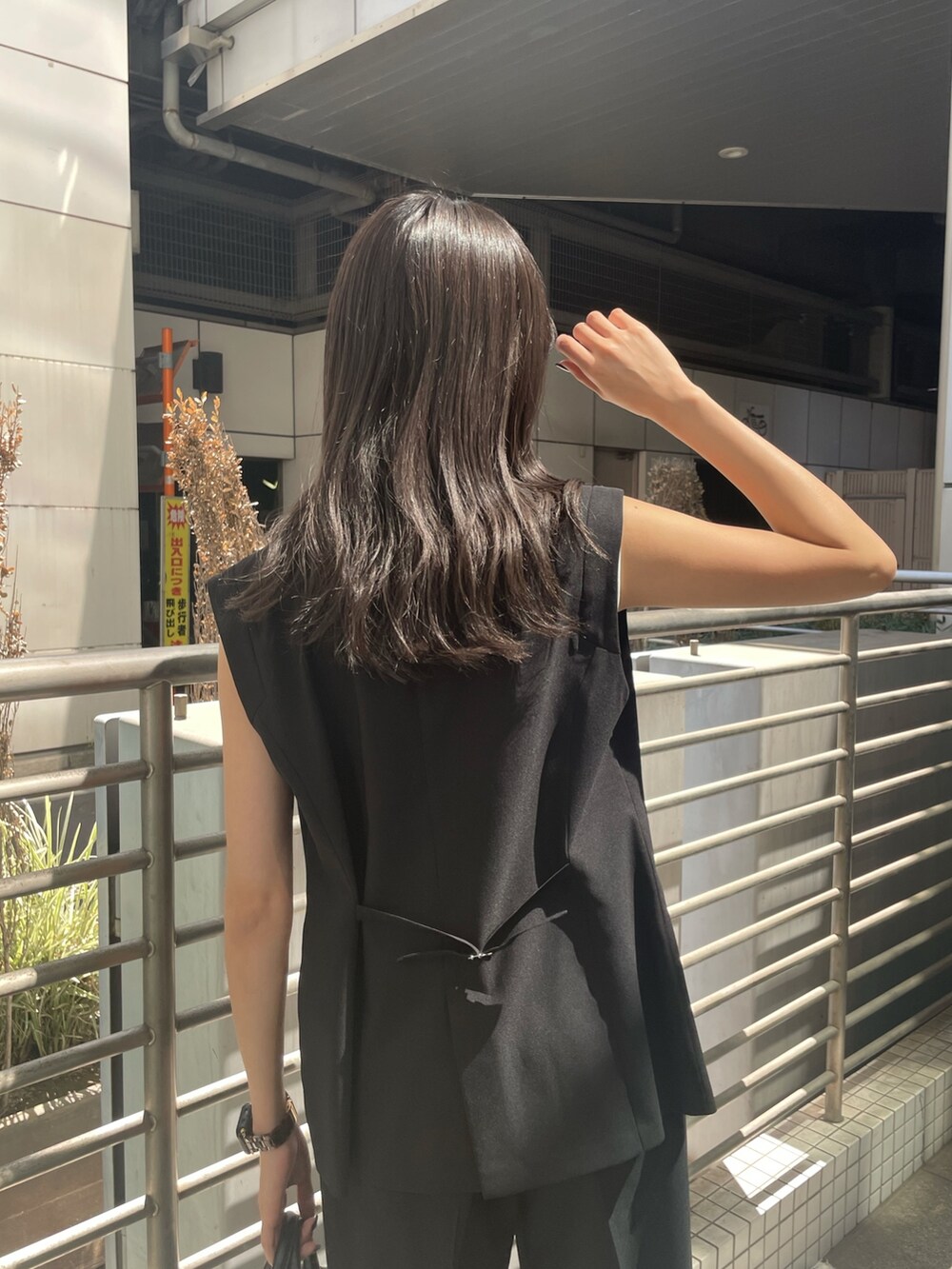 ブラック系のテーラードジャケット、ホワイト系のタンクトップ、ブラック系のスラックスを着用したレディースの春コーディネートの5枚目の写真