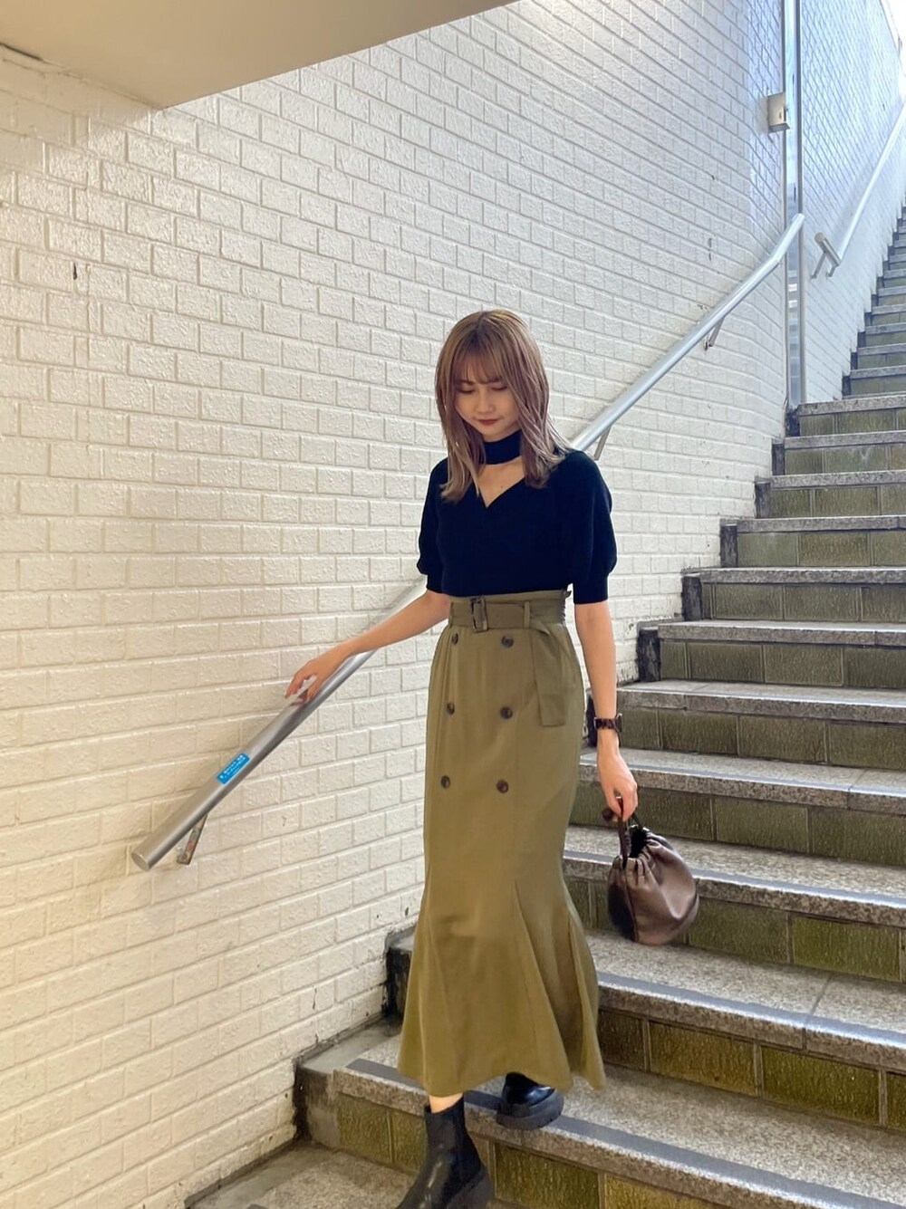 ベージュ系のスカート、ブラック系のニット/セーターを着用したレディースの夏コーディネートの2枚目の写真