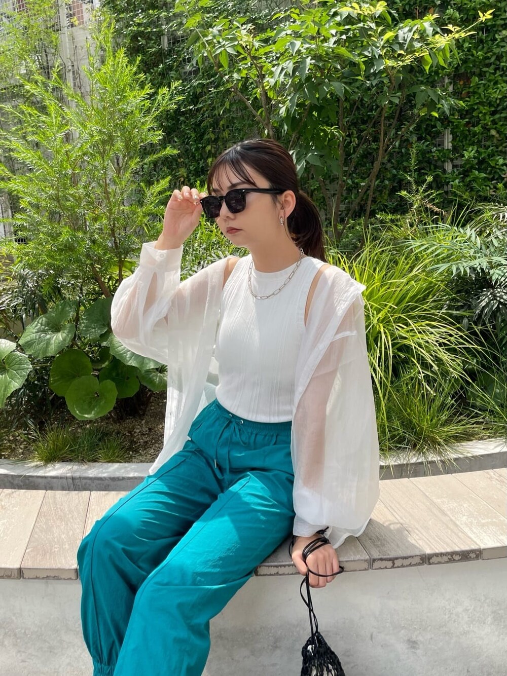 ブラック系のハンドバッグ、ホワイト系のシャツ/ブラウス、ブラック系のサンダルを着用したレディースの夏コーディネートの4枚目の写真