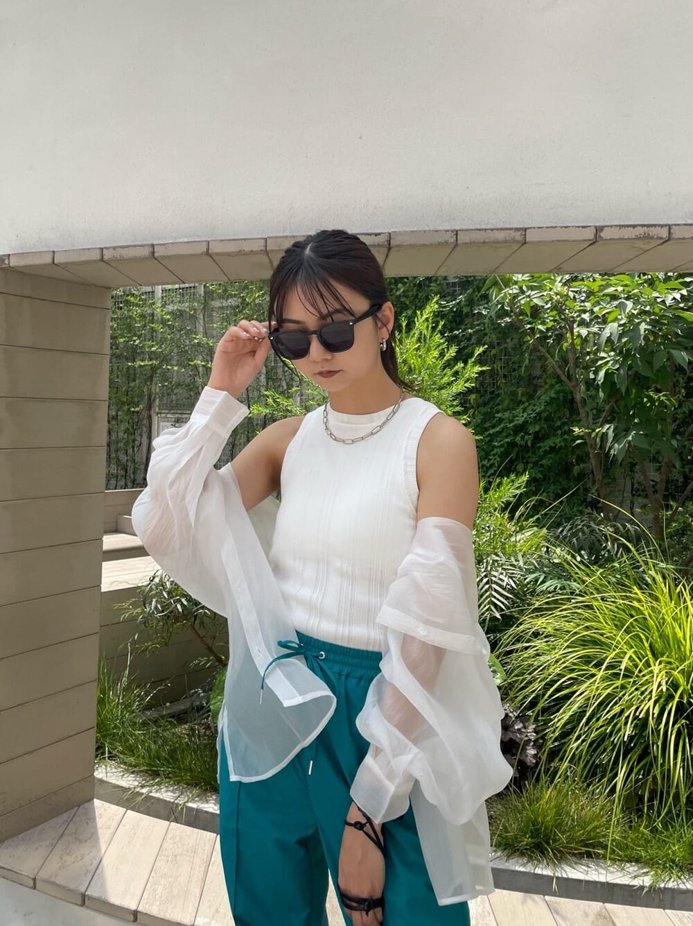 ブラック系のハンドバッグ、ホワイト系のシャツ/ブラウス、ブラック系のサンダルを着用したレディースの夏コーディネートの3枚目の写真