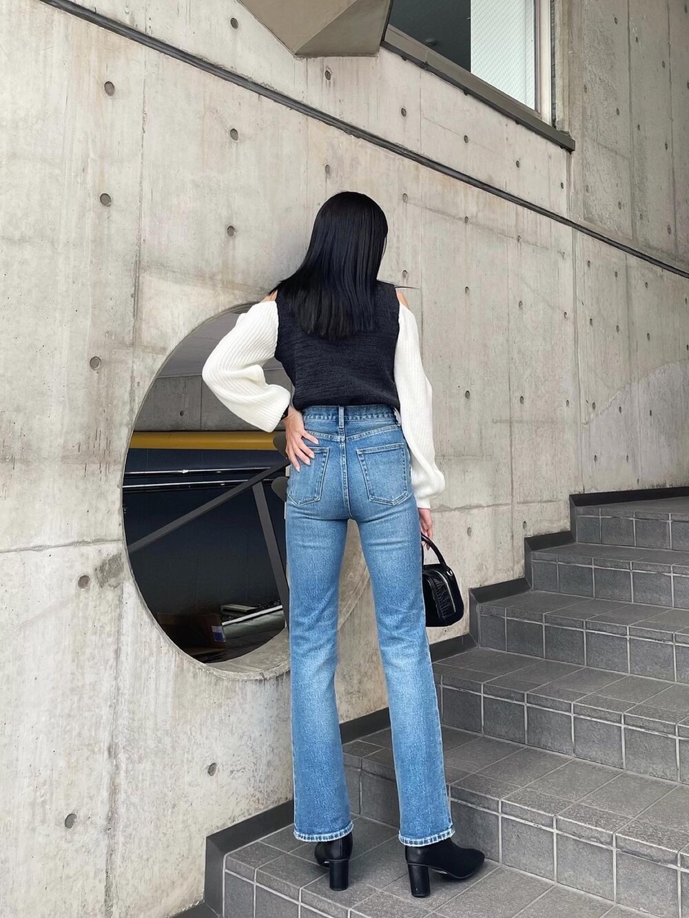 ブラック系のニット/セーター、ブラック系のブーツ、ブルー系のデニムパンツを着用したレディースの秋コーディネートの3枚目の写真