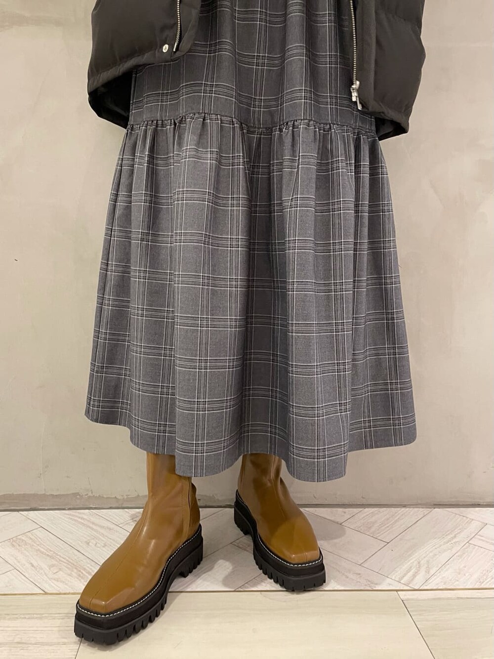 ブラック系のダウンベスト、その他のスカート、ブラウン系のブーツを着用したレディースの秋コーディネートの4枚目の写真