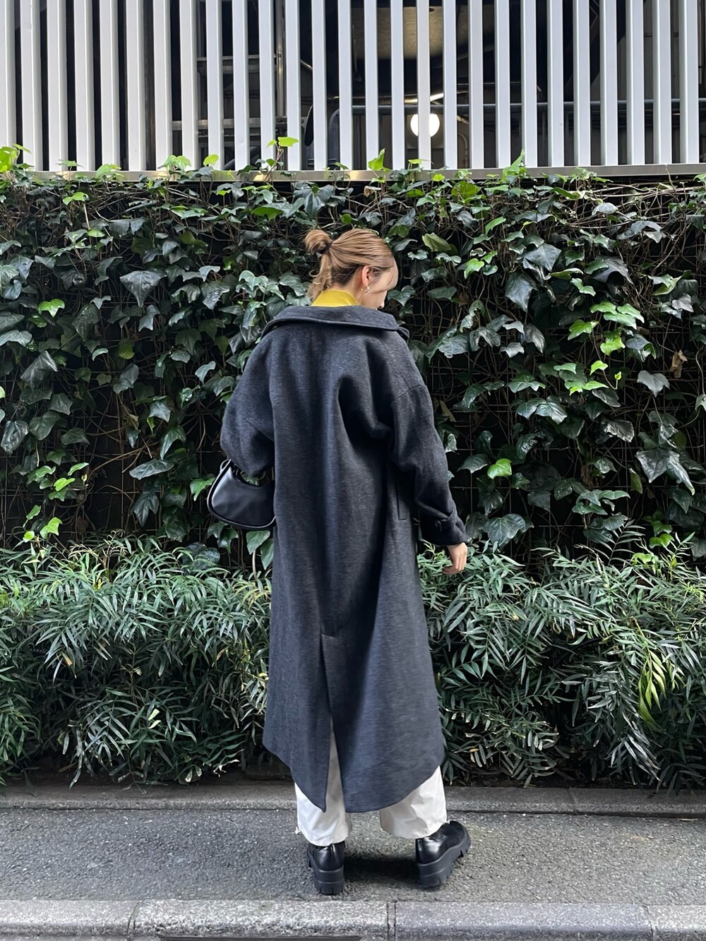 グリーン系のステンカラーコート、ホワイト系のカーゴパンツ、グリーン系のハンドバッグを着用したレディースの秋コーディネートの2枚目の写真