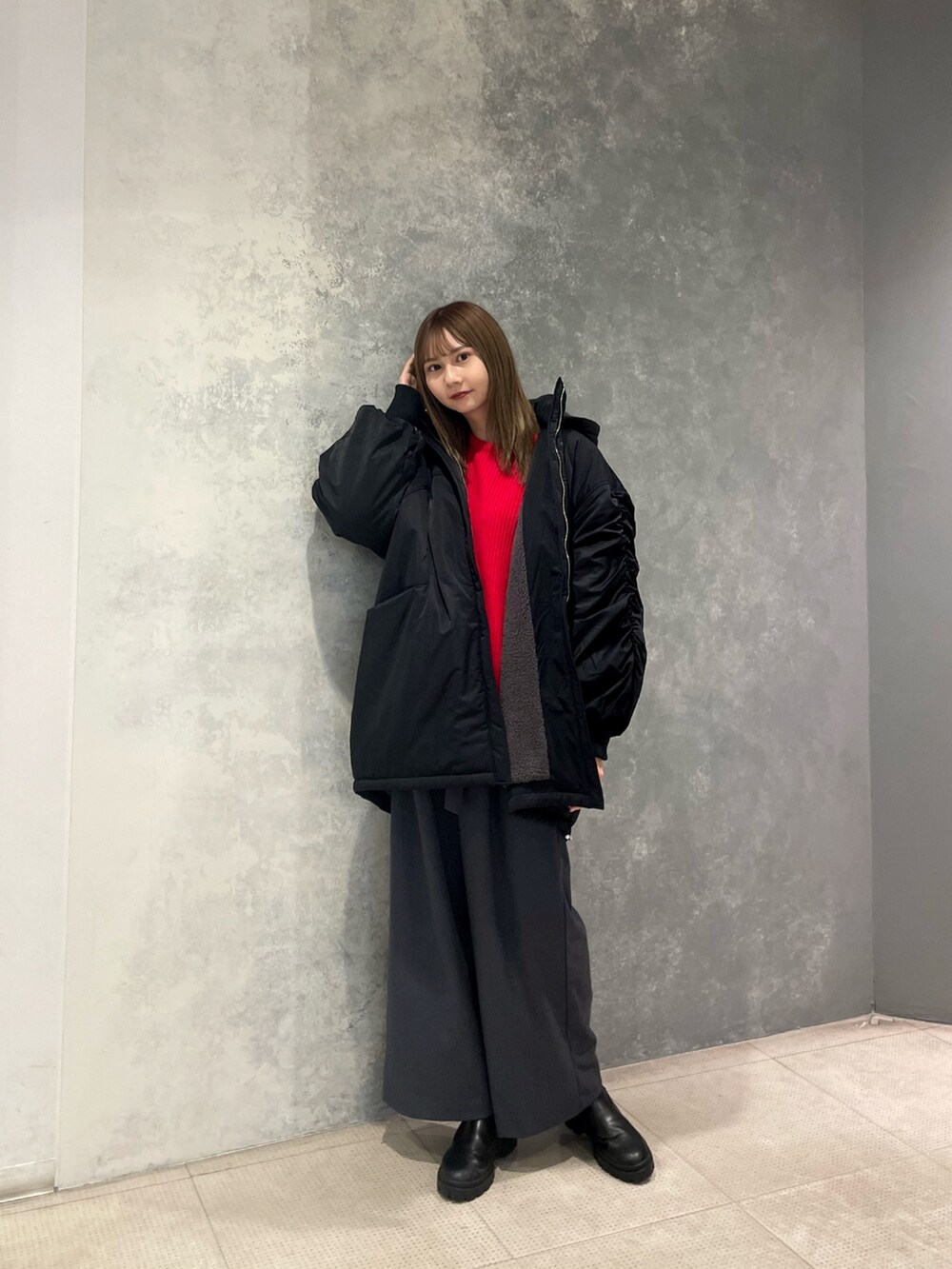 レッド系のニット/セーター、ブラック系のブルゾン、グレー系のスラックスを着用したレディースの冬コーディネートの2枚目の写真
