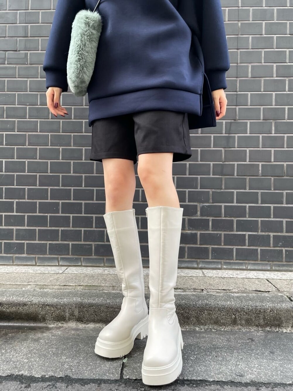 ホワイト系のブーツ、ベージュ系のショルダーバッグ、ブルー系のパーカーを着用したレディースの秋コーディネートの7枚目の写真