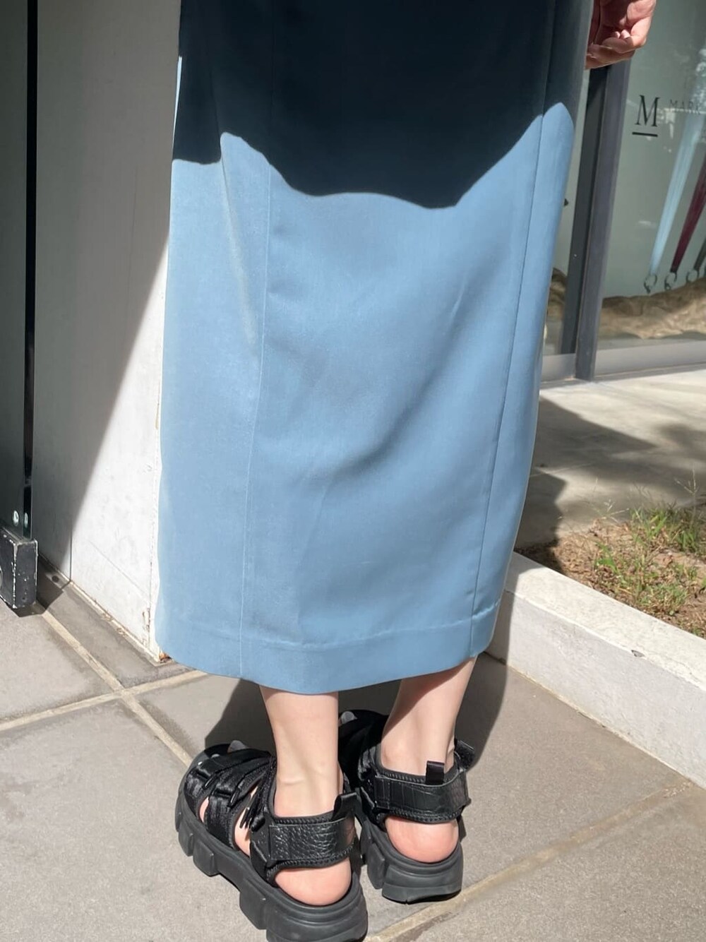 ブルー系のスカート、ブルー系のベスト、ブラック系のサンダルを着用したレディースの夏コーディネートの5枚目の写真