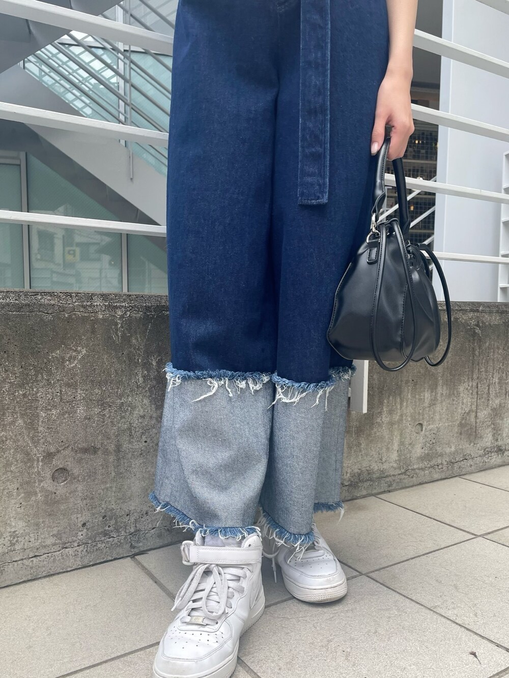 ブルー系のニット/セーター、ブラック系のハンドバッグ、ブルー系のデニムパンツを着用したレディースの春コーディネートの5枚目の写真