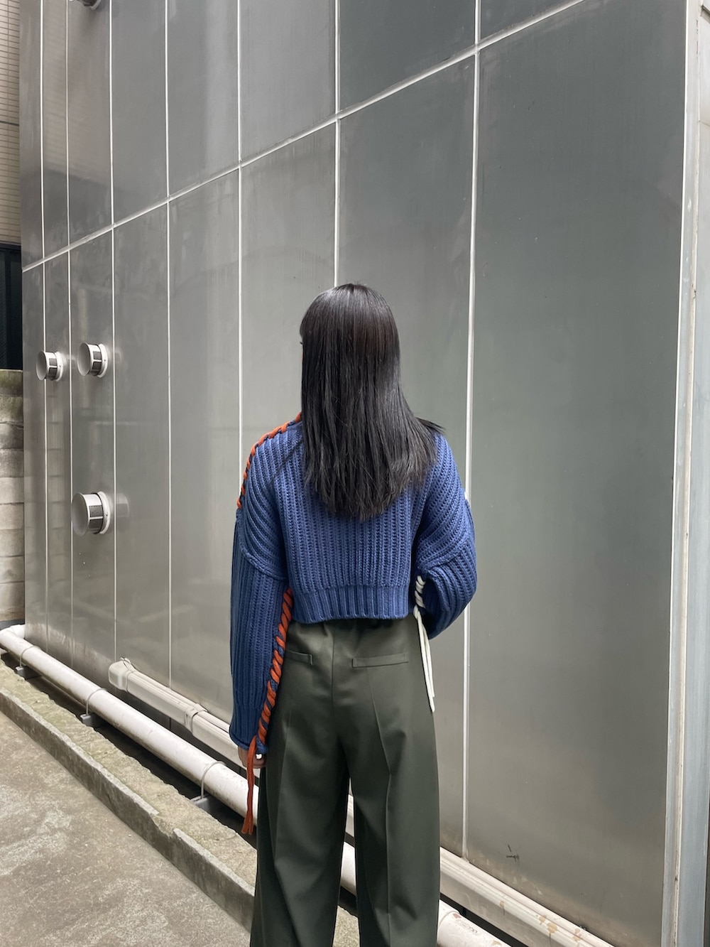 ブルー系のニット/セーター、グリーン系のスラックス、ブラック系のブーツを着用したレディースの夏コーディネートの5枚目の写真