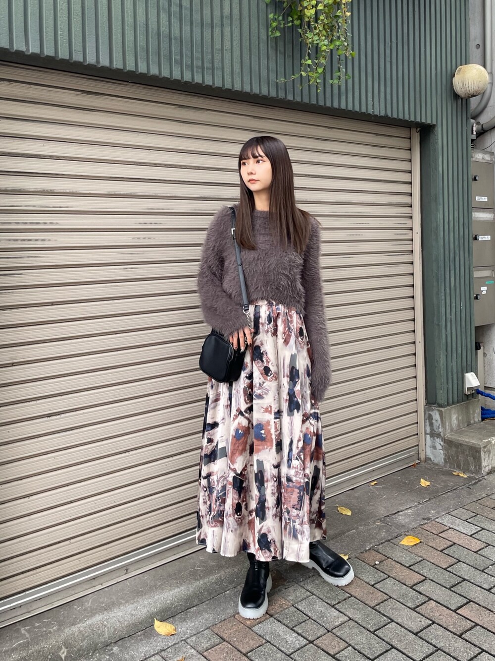 グレー系のニット/セーター、ブラック系のブーツ、ブルー系のスカートを着用したレディースの秋コーディネートの2枚目の写真