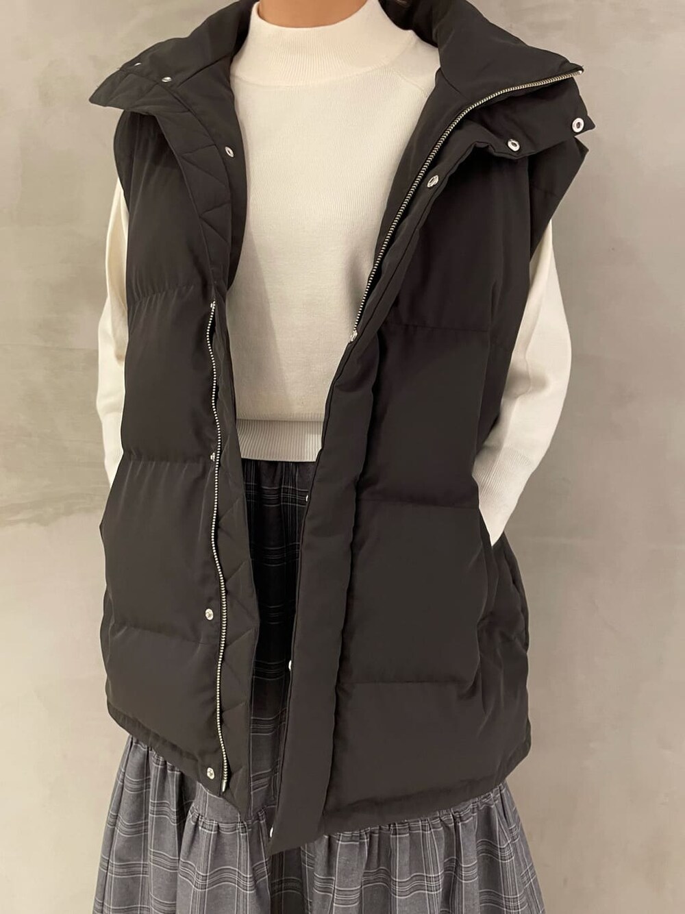 ブラック系のダウンベスト、その他のスカート、ブラウン系のブーツを着用したレディースの秋コーディネートの5枚目の写真