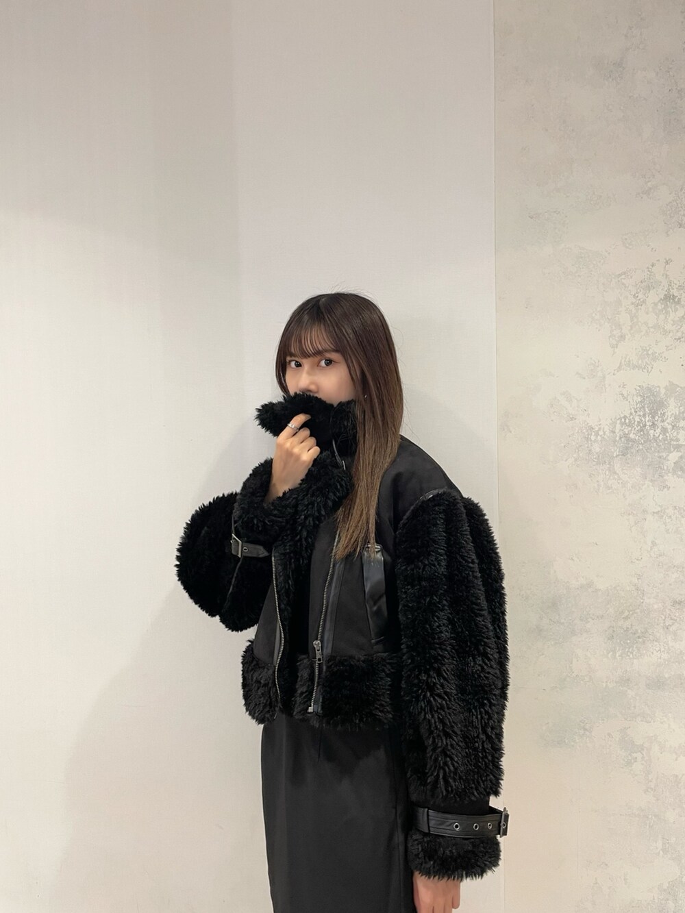 ブラック系のムートンコート、イエロー系のニット/セーター、ブラック系のスカートを着用したレディースの秋コーディネートの5枚目の写真