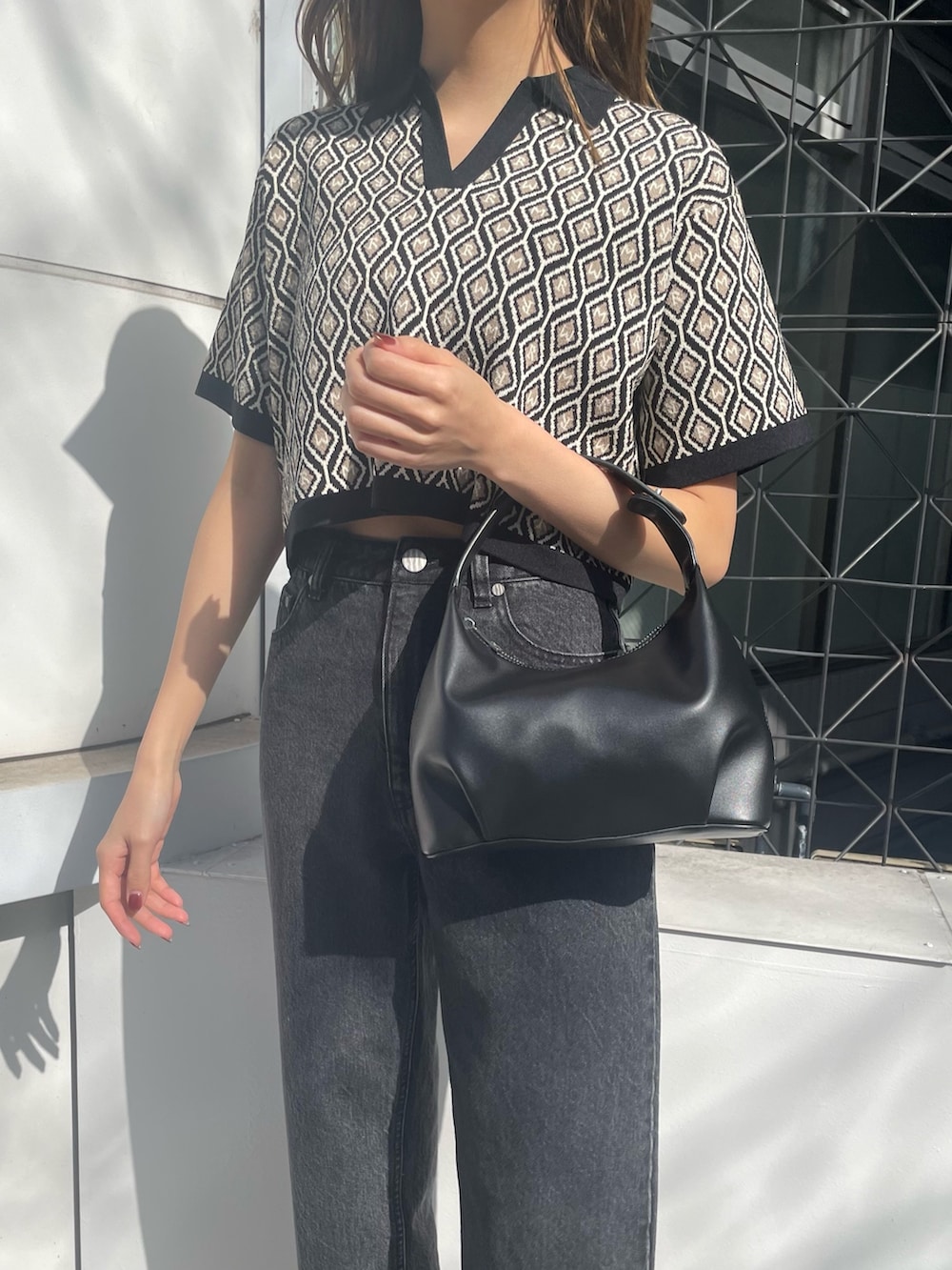 ブラック系のデニムパンツ、ブラック系のサンダル、ブラック系のポロシャツを着用したレディースの冬コーディネートの6枚目の写真