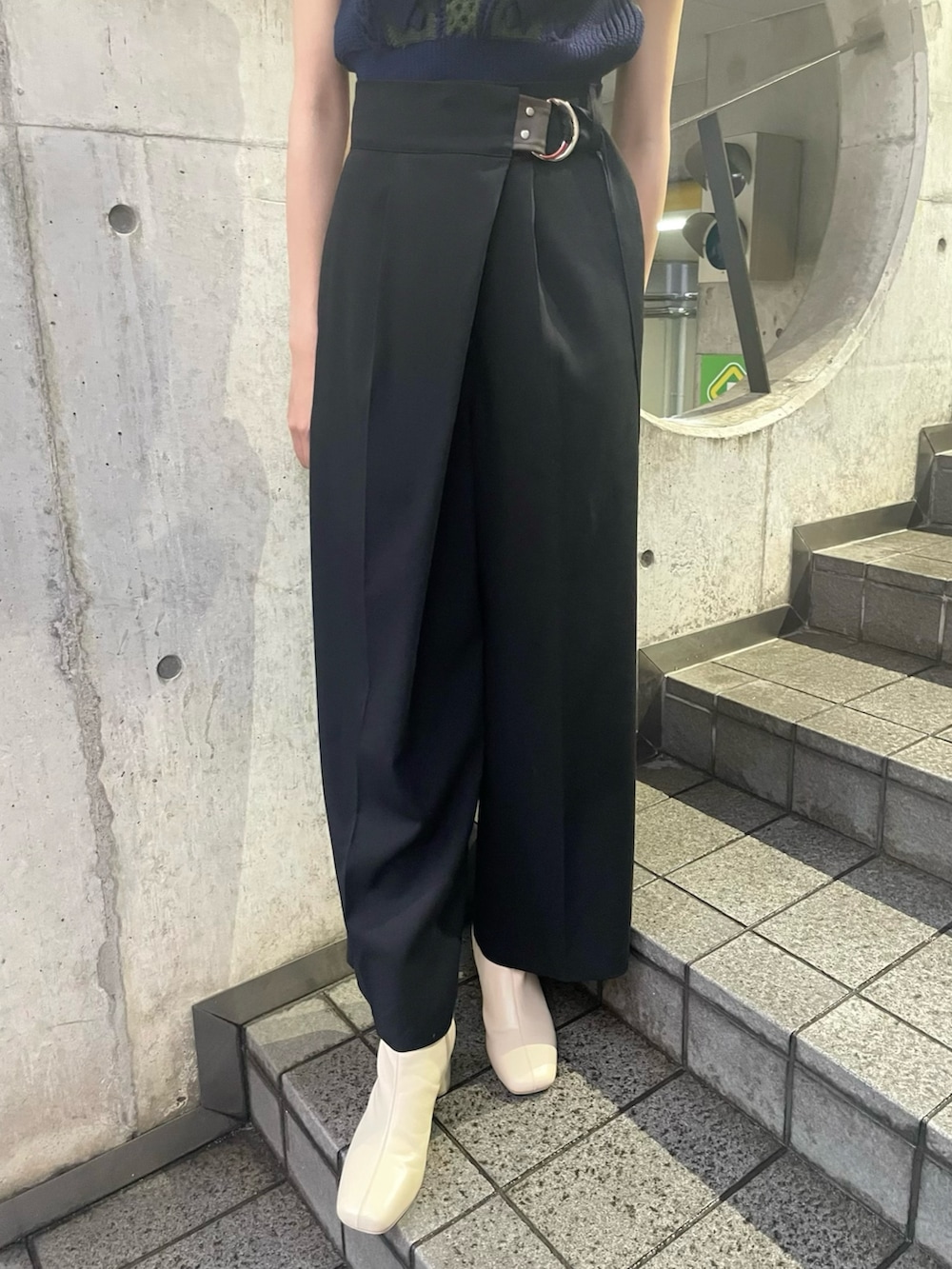 グリーン系のニット/セーター、ブラック系のスラックス、ホワイト系のブーツを着用したレディースの夏コーディネートの5枚目の写真