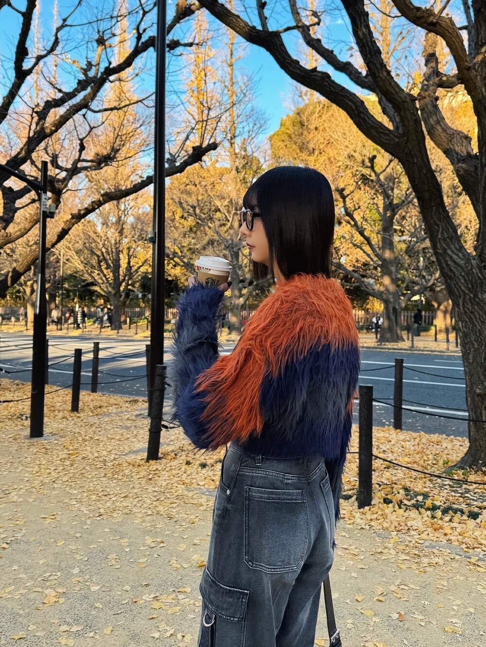 オレンジ系のニット/セーター、ブラック系のデニムパンツ、ブラック系のブーツを着用したレディースの冬コーディネートの3枚目の写真