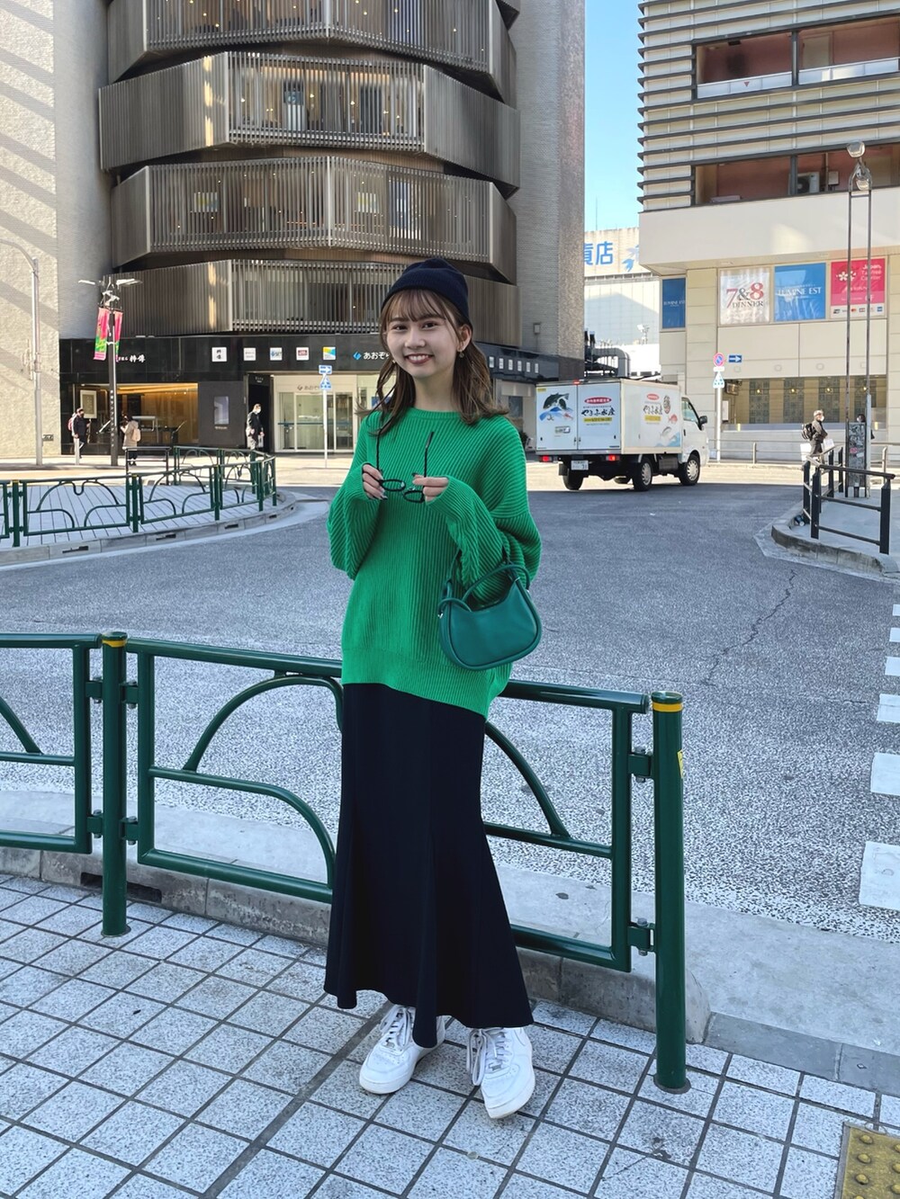 グリーン系のニット/セーター、グリーン系のハンドバッグ、ブラック系のスカートを着用したレディースの冬コーディネートの2枚目の写真
