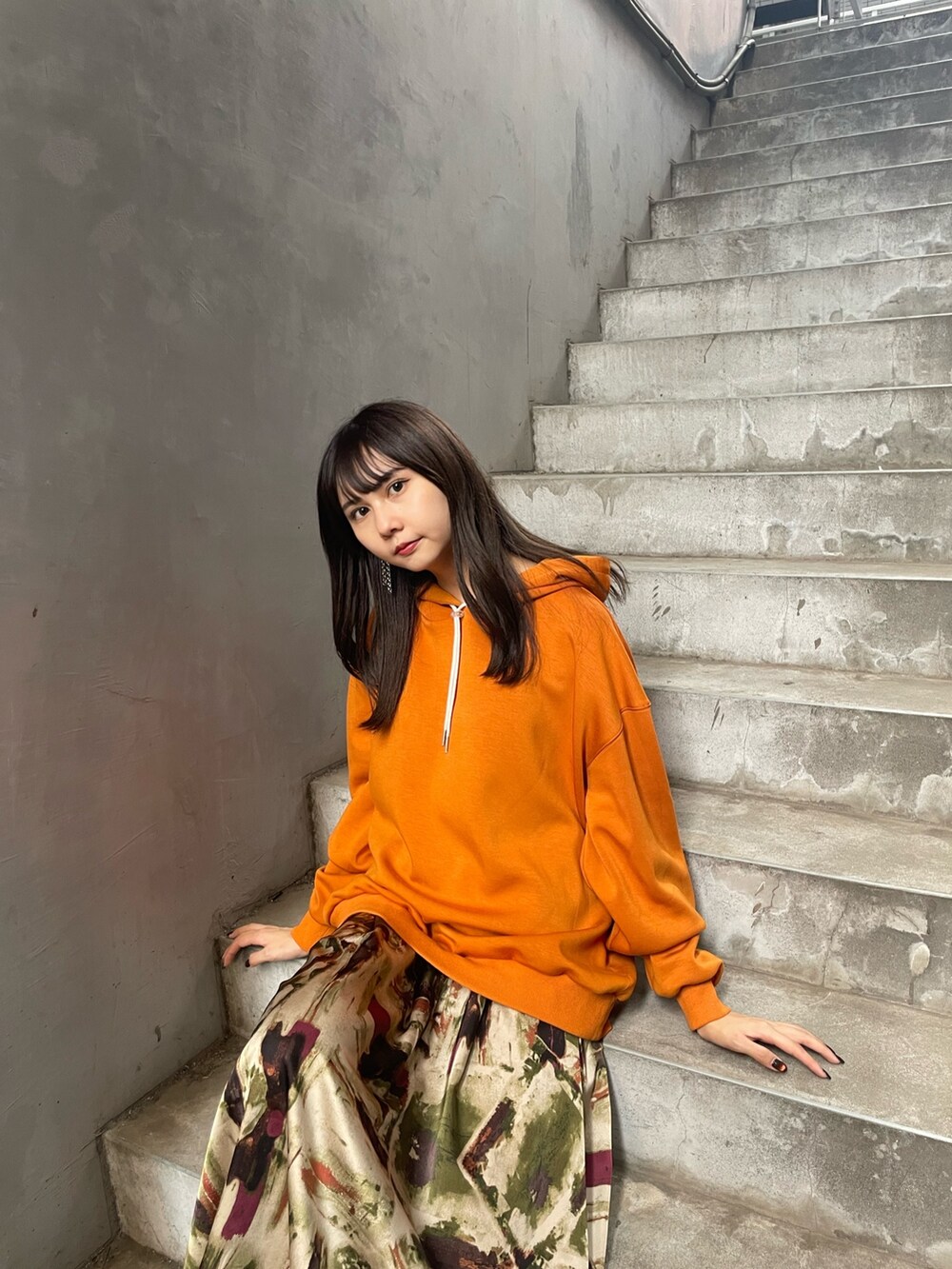 オレンジ系のパーカー、グリーン系のスカート、ホワイト系のブーツを着用したレディースの夏コーディネートの4枚目の写真