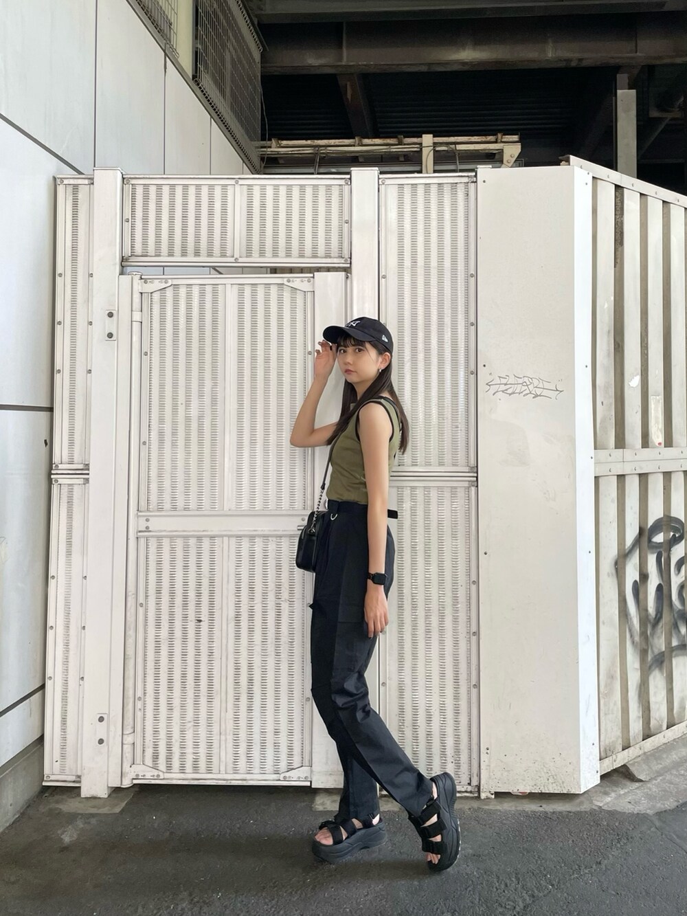 ベージュ系のタンクトップ、ブラック系のカーゴパンツ、ブラック系のサンダルを着用したレディースの夏コーディネートの2枚目の写真